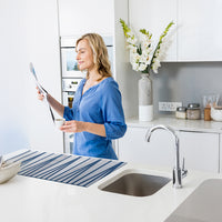 Immagine di una donna in cucina che usa la Passatoia Cucina Snoopy Dance mentre legge un documento.